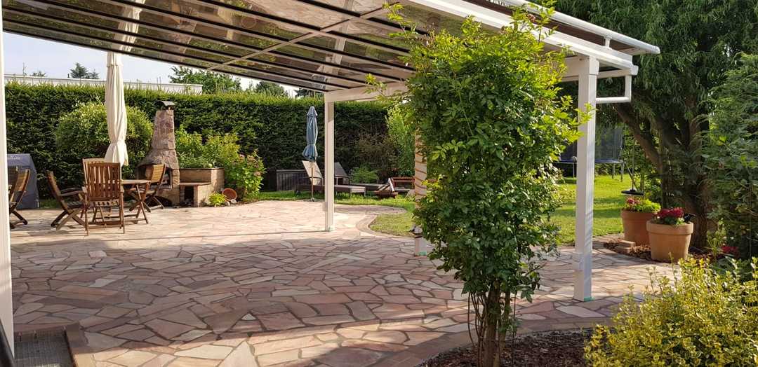 Natursteinterrasse mit Sitzbereich, Überdachung und bepflanztem Garten Natursteinterrasse mit Sitzbereich, Überdachung und bepflanztem Garten
